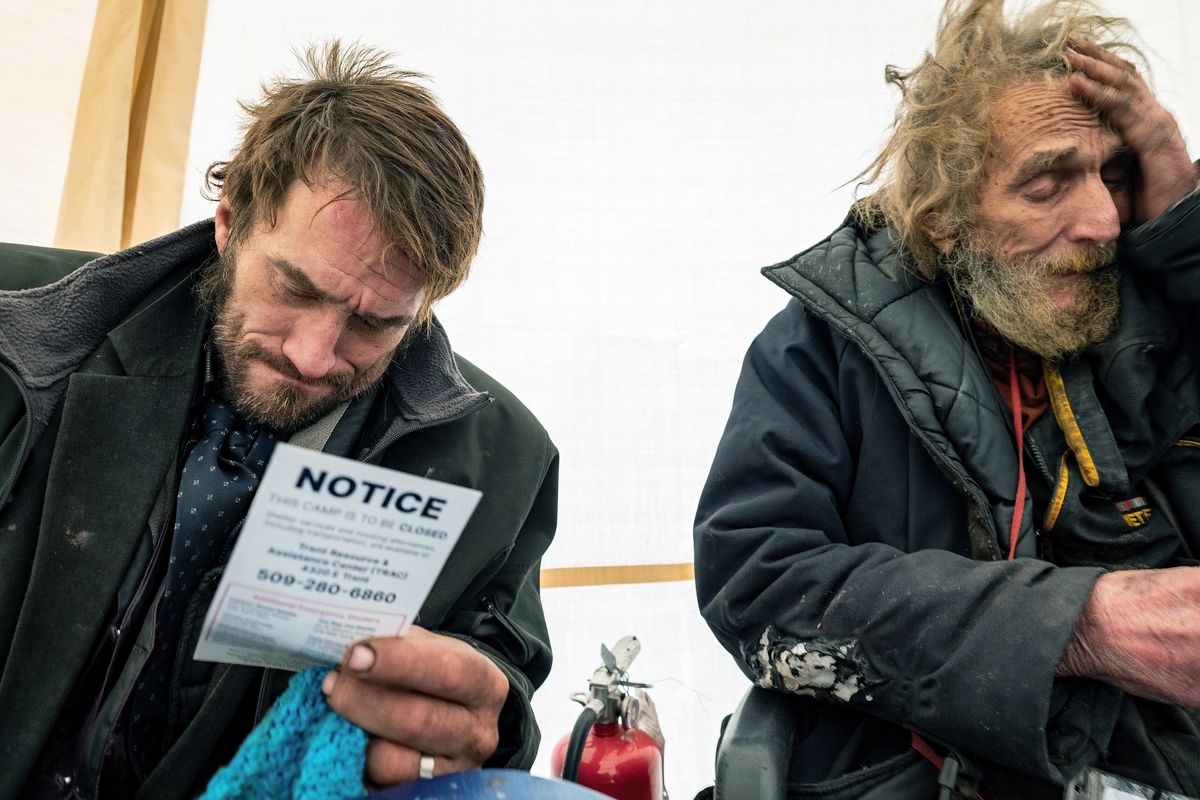 Lonnie Goin, on left, and his father, Lonnie Goin Sr., were given flyers handed to Camp Hope residents Tuesday by the Spokane County Sheriff’s Office and the Spokane Police Department stating the homeless camp is closing.  (COLIN MULVANY/THE SPOKESMAN-REVIEW)