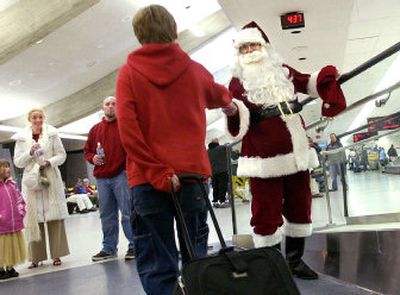 
Santa, aka Eugene LaLiberte, passes out candy canes at Spokane International Airport on Sunday. LaLiberte of Liberty Lake has been visiting the airport on Christmas Eve for more than 30 years. 
 (Joe Barrentine / The Spokesman-Review)