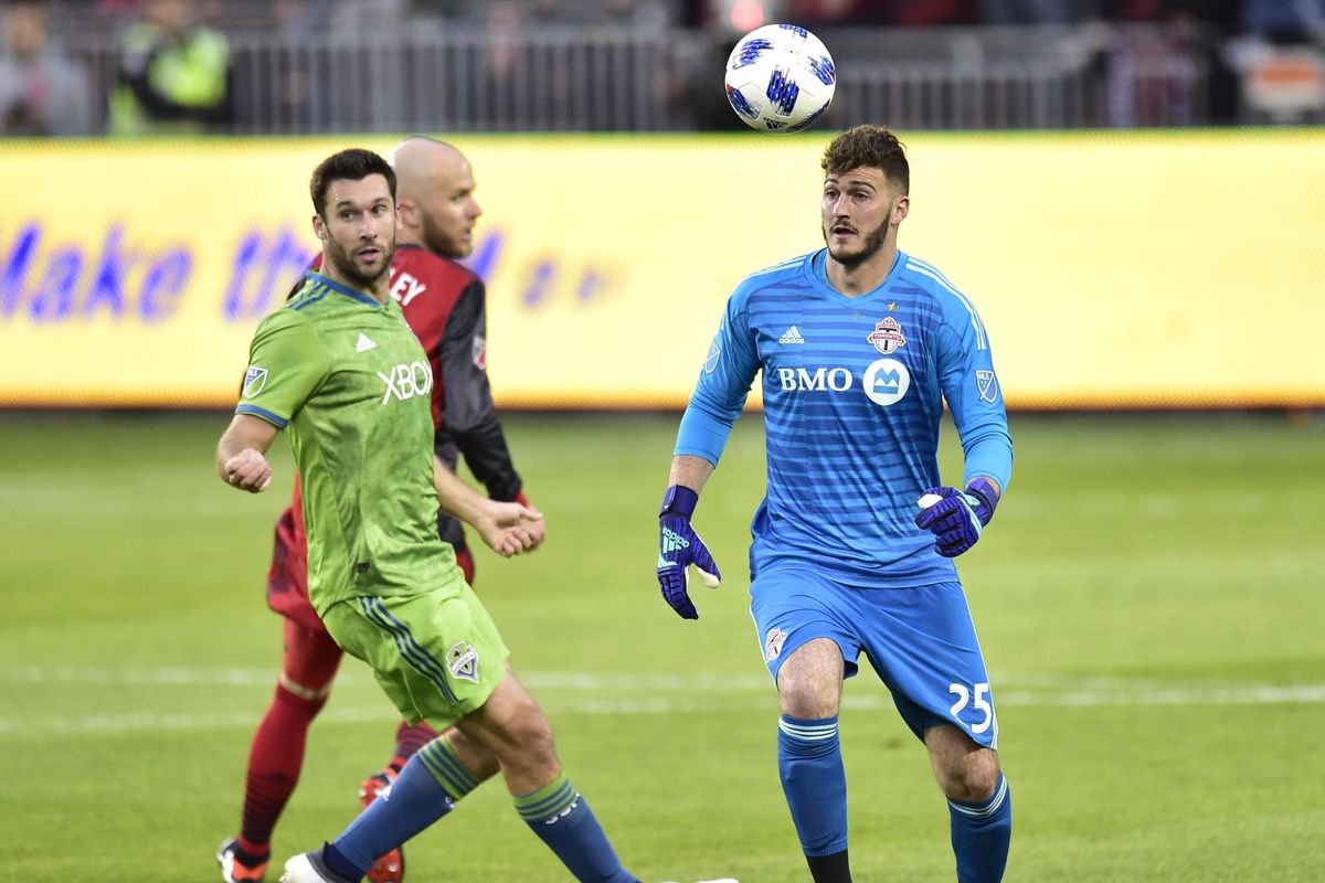 Toronto FC goalkeeper Alex Bono comes out of the penalty area to play the ball next to Seattle Sounders