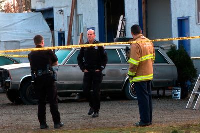 Spokane police officers and firefighters  assess the scene Wednesday at Empire Auto Body in northeast Spokane, where a man died in a shop fire.  (Colin Mulvany / The Spokesman-Review)
