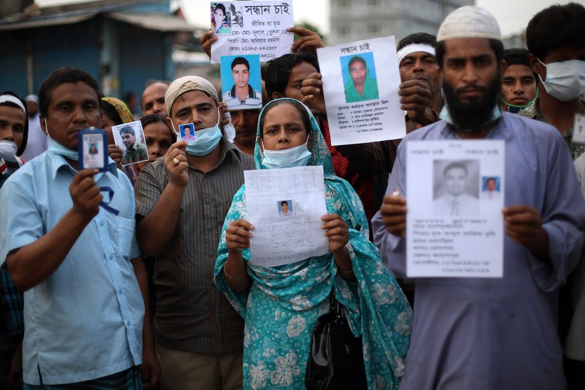 Relatives of missing victims gather Sunday holding pictures of their loved ones at the site of the garment factory building that collapsed Wednesday in Savar, Bangladesh. (Associated Press)