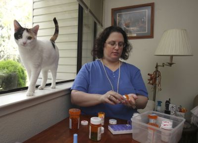 Melody Nolan, who suffers from an autoimmune illness that has blinded and paralyzed her in the past, prepares her medications in Sacramento, Calif.  (Associated Press / The Spokesman-Review)