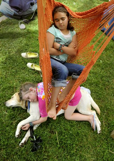 All aboard for ArtFest: Tyra Kelly, 11, relaxes in a custom hammock as her friend Dita Masak, 5, lounges on a dog named Tagish on Friday during ArtFest at Coeur d’Alene Park in Browne’s Addition. If you go: Spokane’s annual art fair, featuring 160 vendors, continues today from 10 a.m. to 8 p.m. and Sunday from 10 a.m. to 5 p.m. Admission is free. (Colin Mulvany)