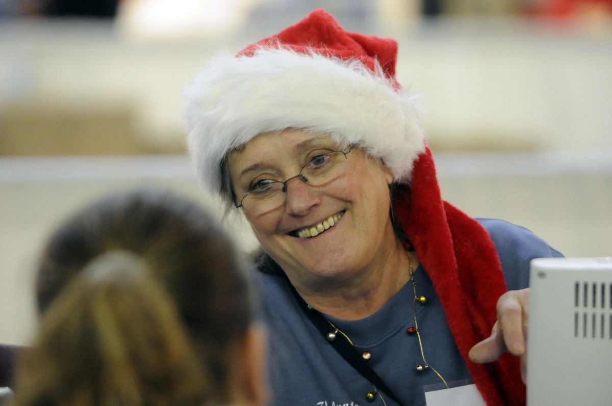 Volunteer Judy Doyle finishes verifying a client’s needs before sending  her off to shop at the Christmas Bureau on Saturday.  (Photos by JESSE TINSLEY / The Spokesman-Review)