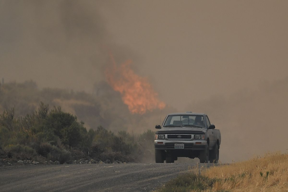 A pickup drives down a dirt road as the Pearl Hill Fire