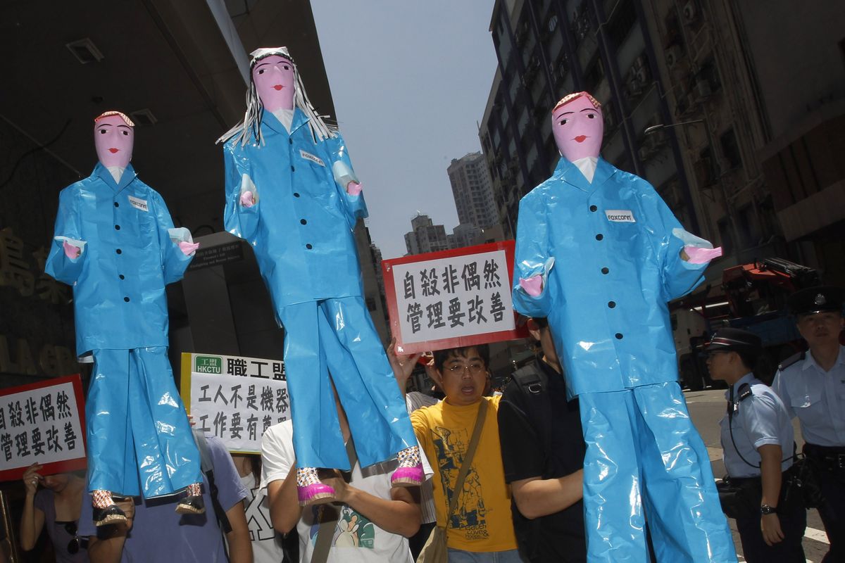 A dozen labor activists carry paper figures in a protest near the Foxconn office in Hong Kong. A 19-year-old Chinese employee of Foxconn Technology Group jumped from a building on Tuesday and died. Associated Press photos (Associated Press photos)