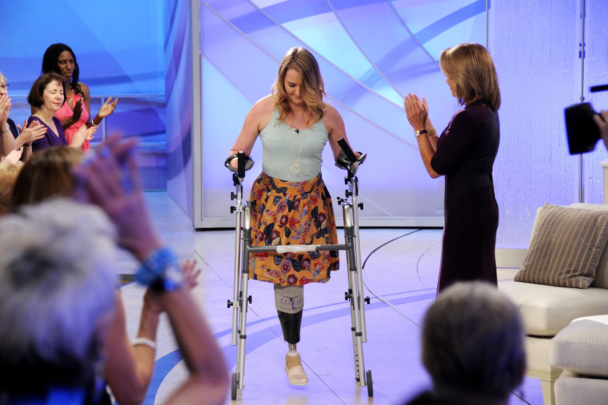 This image released by Disney-ABC Domestic Television shows host Katie Couric, right, applauding as Aimee Copeland, 24, of Snellville, Ga., who survived a rare fleshing-eating disease, as she arrives for an exclusive interview on the new daytime talk show "Katie," Tuesday, Sept. 11, 2012, in New York. Copeland walked to the stage using a new walker. Copeland was joined in New York by her parents and sister. After Couric interviewed the family, she announced that an Atlanta-area Chevrolet dealer was in the studio to give Copeland a new minivan that will be retrofitted so she can drive it. Copeland got the infection in May after falling from a zip line and gashing her leg. Doctors had to amputate both hands, her left leg and right foot. She returned home to suburban Atlanta last week after three months in the hospital and a rehabilitation clinic. (Ida Astute / Disney-abc Domestic Television)