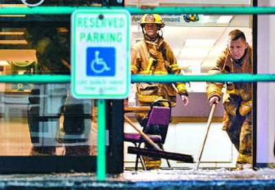
Spokane firefighters use squeegees to clean up the floors of the Department of Social and Health Services after  the roof collapsed from heavy rain Monday. 
 (Jed Conklin / The Spokesman-Review)