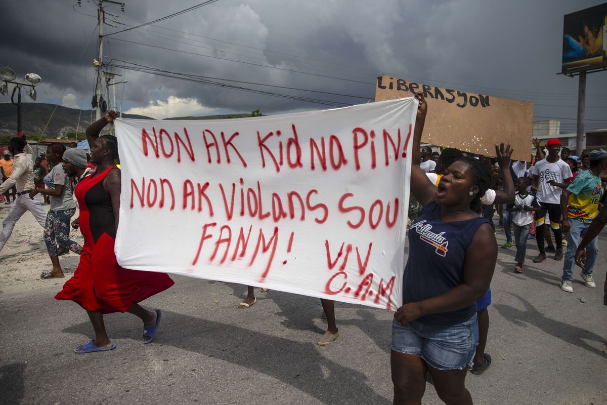 People protest carrying a banner with a message that reads in Creole: "No to kidnappings, no to violence against women ! Long live Christian Aid Ministries," demanding the release of kidnapped missionaries, in Titanyen, north of Port-au-Prince, Haiti, Tuesday, Oct. 19, 2021. A group of 17 U.S. missionaries including children was kidnapped by a gang in Haiti on Oct. 16.  (Odelyn Joseph)