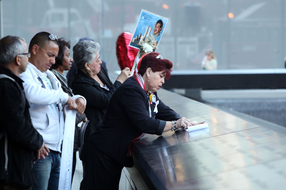 Rosario Tejada, right, of Columbia makes as rubbing of the name of her nephew, Wilder Gomez, of the Queens borough of New York, who died in the north tower of the World Trade Center. She is attending the observances held on the eleventh anniversary of the attacks on the World Trade Center, in New York, Tuesday Sept. 11, 2012. (Chris Pedota / The Record)