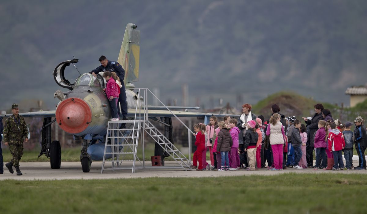 FILE - In this Thursday, April 10, 2014 file picture, Romanian children, visiting an airbase, wait to get a close look at a Soviet era Romanian MIG 21 fighter jet in Campia Turzii, Romania. The U.S. Air Force has deployed on Monday, Jan. 4, 2021, about 90 airmen and an unspecified number of drone aircraft to a base in central Romania, boosting its military presence in the region where there are allied concerns that Russia is trying to display its military strength.  (Vadim Ghirda)