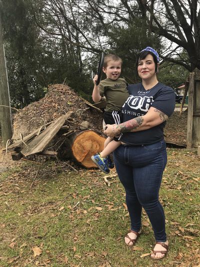 Lilly Langworth and her 3-year-old son Max stand in front of an oak tree felled by Hurricane Michael on Oct. 25, 2018, in the front yard of their Chipley, Fla., home. Langworth said she's watching for signs of trauma among her three children following the storm. (Tamara Lush / Associated Press)