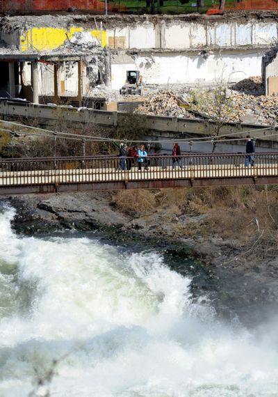 River on a tear down by Y: Strollers pause on the bridge to Havermale Island in front of the partially demolished YMCA to watch the falls on Friday. (Jesse Tinsley)