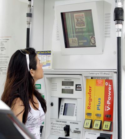 Paloma Peralta looks at a TV monitor as she refuels her car at a gas station in Miami.   Three privately held companies have placed more than 20,000 screens at thousands of stations from Massachusetts to Southern California. (Associated Press / The Spokesman-Review)