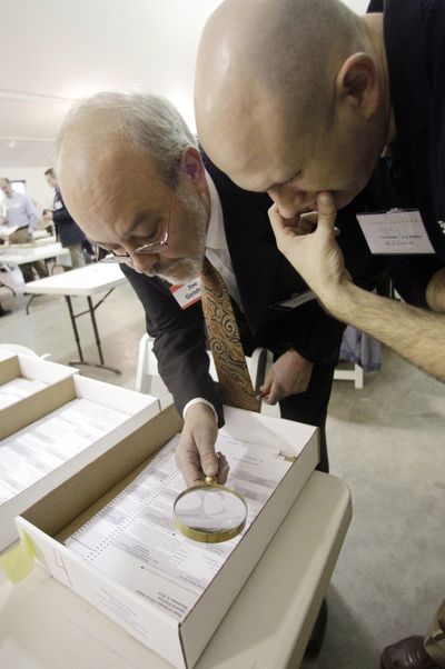 Election observers for Lisa Murkowski and Joe Miller examine a signature on a ballot Thursday in Juneau, Alaska.  (Associated Press)