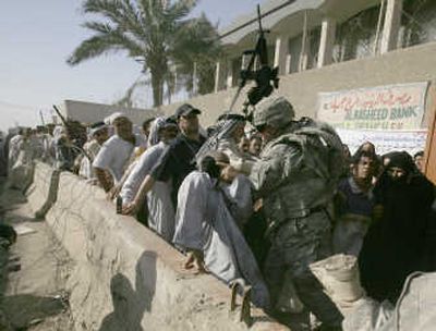 
Sgt. Kyle Hale  hits a man as he contains an unruly crowd to protect another man who was nearly trampled outside the Al Rasheed Bank in the Jamilah market in Sadr City, Iraq, on Tuesday. Associated Press
 (Associated Press / The Spokesman-Review)