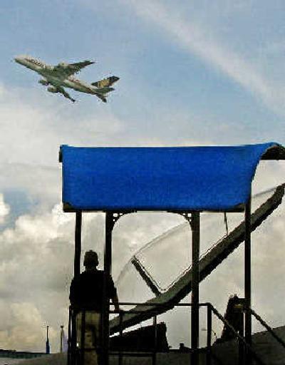 
An Airbus A380 superjumbo airplane flies as a man watches on from the ground level during the Asian Aerospace exhibition in Singapore. 
 (Associated Press / The Spokesman-Review)