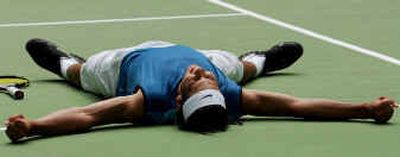 
Spain's Rafael Nadal lies on the court  after a second-round win over Russia's Mikhail Youzhny, 6-1, 4-6, 4-6, 7-5, 6-3.
 (Associated Press / The Spokesman-Review)
