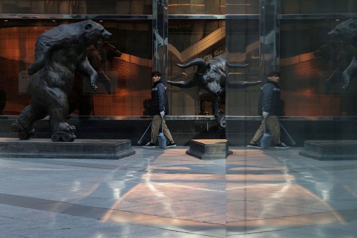 A street cleaner walks near sculptures on Oct. 2 at the foot of skyscrapers of the Moscow International Business Center, also known as Moskva-City, in Moscow, Russia. (Ramil Sitdikov)
