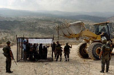 
Palestinian and international activists protest against construction of Israel's separation barrier by locking themselves in a cage in the West Bank village of Bil'in near Ramallah on Wednesday. Israel says the barrier is necessary to keep suicide bombers out, but Palestinians call it a land grab.
 (Associated Press / The Spokesman-Review)