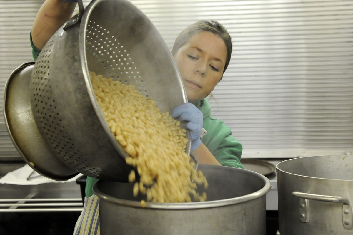 Kitchen assistant Ellerie Easterwood pours navy beans while preparing a meal last week at the House of Charity.