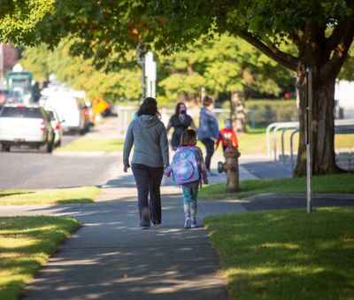 A student holds hands with her guardian while walking up to Regal Elementary School.