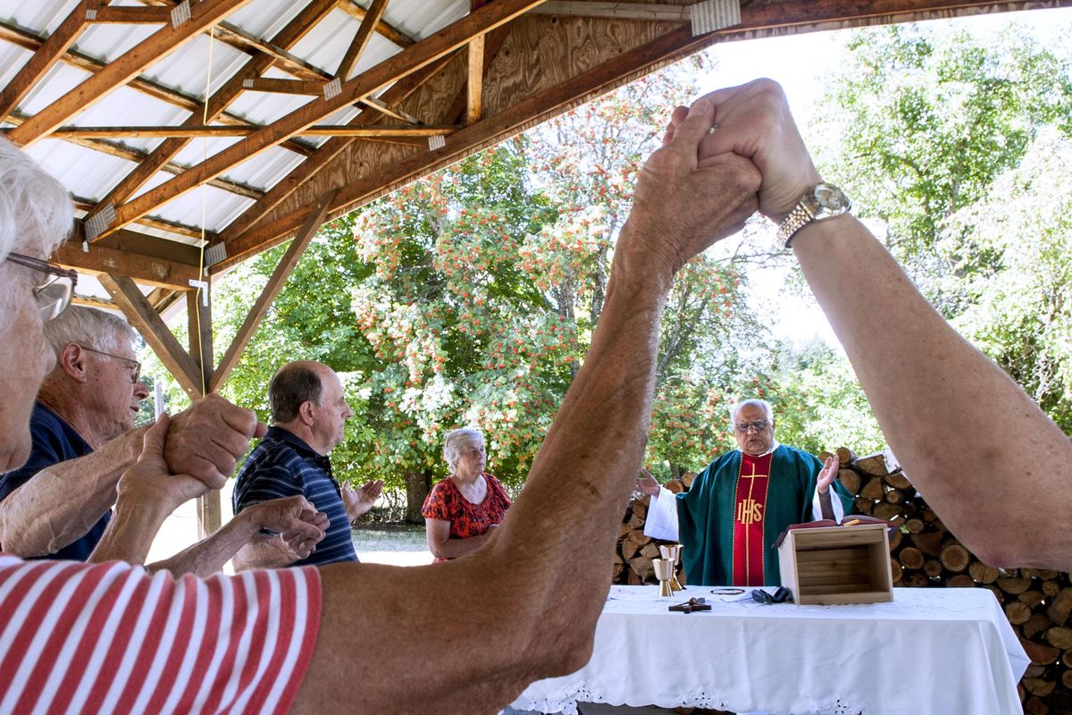 Father Carlos Perez leads Mass outside the former site of St. Ann’s Catholic Church in Bonners Ferry on Wednesday, July 27, 2016. An arson blaze burned the church to the ground April 21, 2016. (Kathy Plonka / The Spokesman-Review)