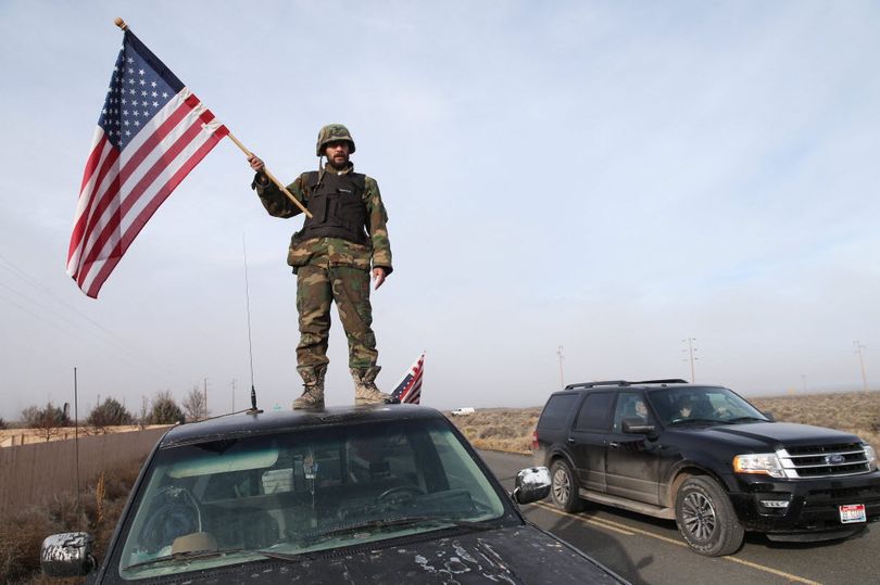 In this Feb. 11, 2016, Oregonian file photo, a man wave American flag from atop a car at the Narrows roadblock, near Burns, Ore. The last four occupiers of a Malheur National Wildlife Refuge in eastern Oregon surrendered Thursday. The holdouts were the last remnants of a larger group that seized the wildlife refuge nearly six weeks ago, demanding that the government turn over the land to locals and release two ranchers imprisoned for setting fires. (Thomas Boyd/The Oregonian via AP)
