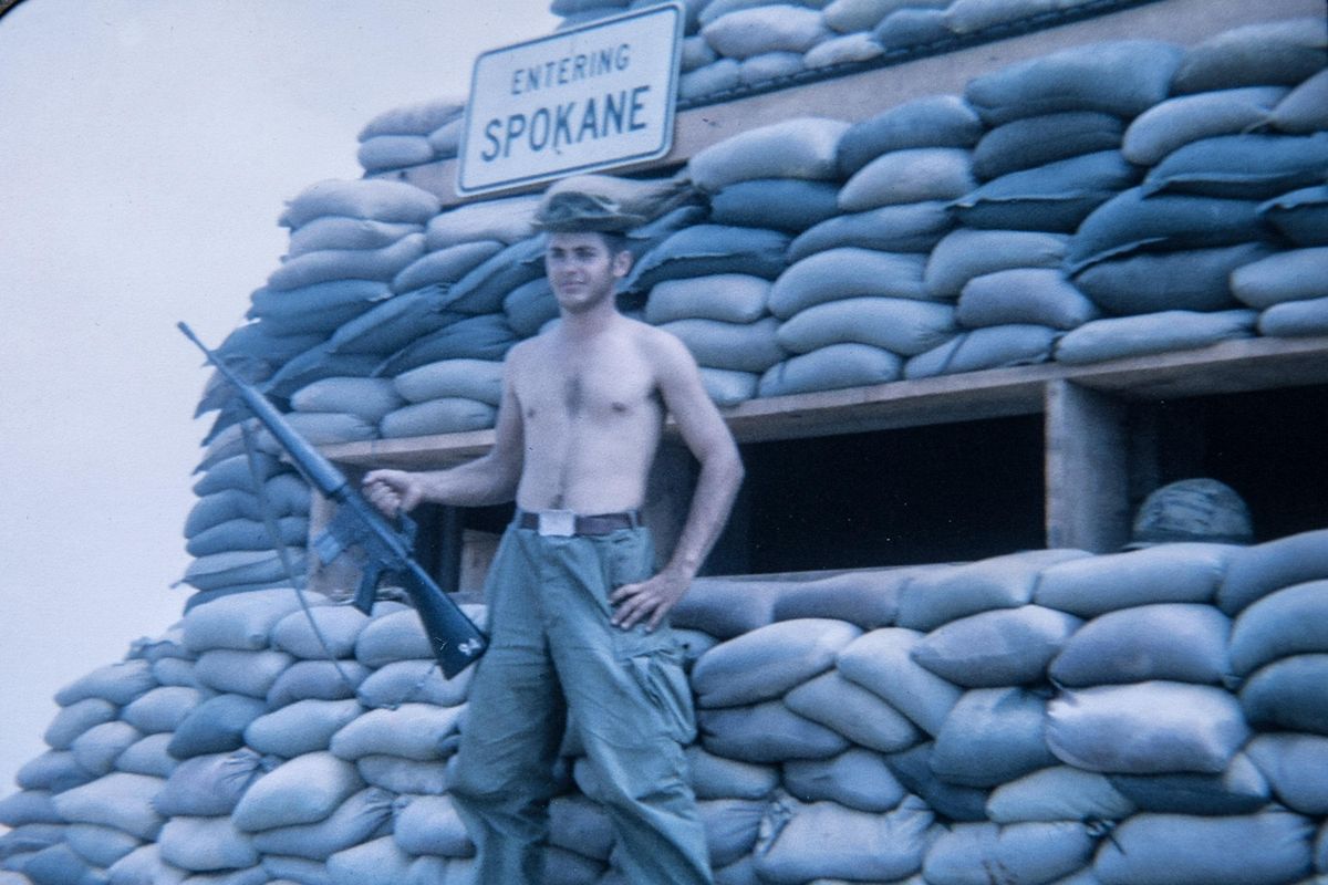 Steve Melville poses with the Entering Spokane sign in Vietnam. Melville’s sister sent the sign, which was  made by the street department, when he was serving in a unit with a few other men from Spokane. (Courtesy photos)