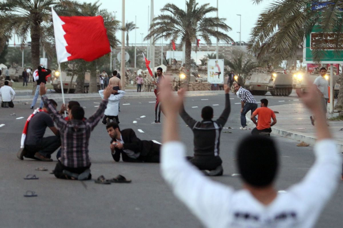 Bahraini protesters who marched toward the Pearl roundabout sit down in the street in front of army tanks Friday in Manama, Bahrain. (Associated Press)