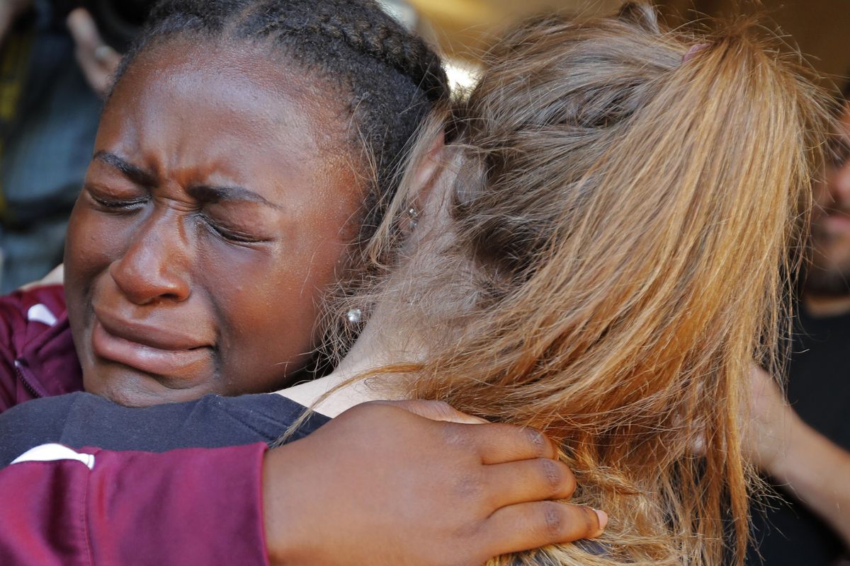 Marla Eveillard, 14, cries as she hugs friends before the start of a vigil Thursday, Feb. 15, 2018, at the Parkland Baptist Church, for the victims of Wednesday