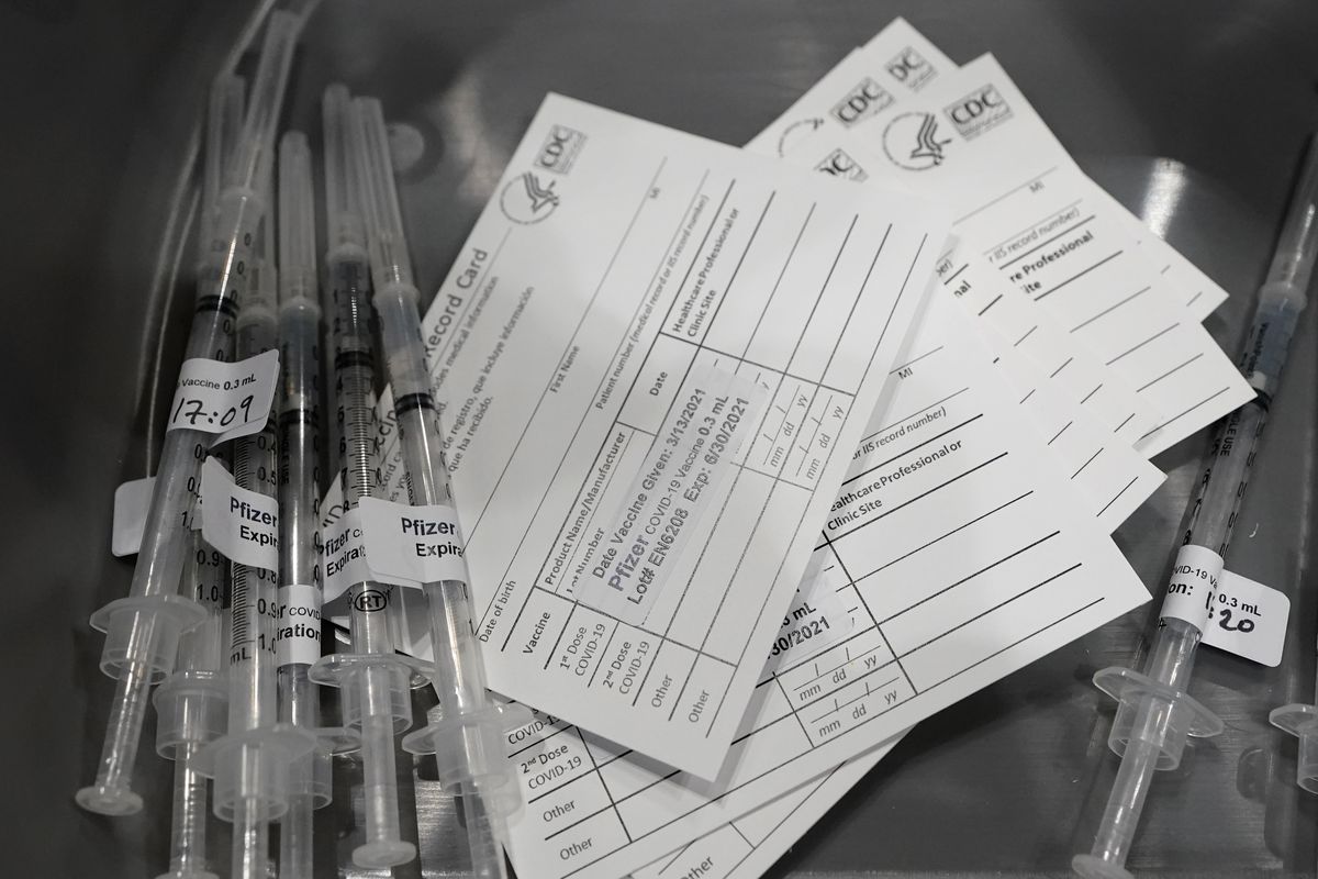 Syringes with doses of the Pfizer COVID-19 vaccine, are shown next to vaccination cards, Saturday, March 13, 2021, on the first day of operations at a mass vaccination site at the Lumen Field Events Center in Seattle, which adjoins the field where the NFL football Seattle Seahawks and the MLS soccer Seattle Sounders play their games. The site, which is the largest civilian-run vaccination site in the country, will operate only a few days a week until city and county officials can get more doses of the vaccine.  (Ted S. Warren)
