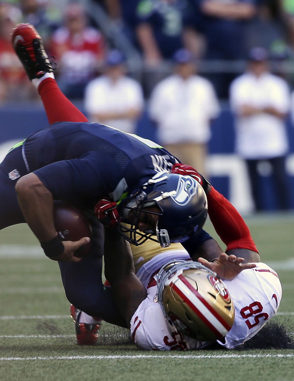 Seattle Seahawks quarterback Russell Wilson, top, is pulled down by San Francisco 49ers