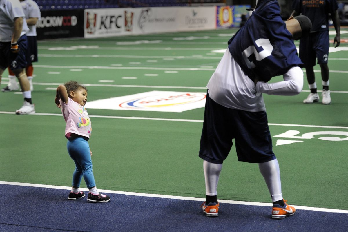 Two-year-old Tiana Sanders, daughter of Shock’s Terrance Sanders, stretches with player Josh Ferguson while visiting practice. (Jesse Tinsley)