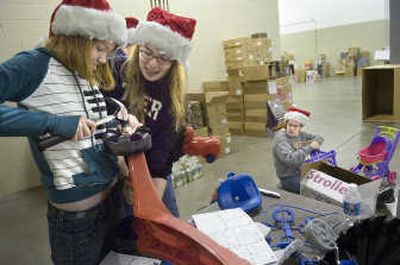 
Lewis and Clark High School students, from left, Justine Hall,  Elyssa Kerr  and Delaney Dittman  assemble toys Wednesday at the Christmas Bureau, housed at the Spokane County Fair and Expo Center. The bureau gives away toys and grocery store vouchers.
 (Photo by CHRISTOPHER ANDERSON / The Spokesman-Review)