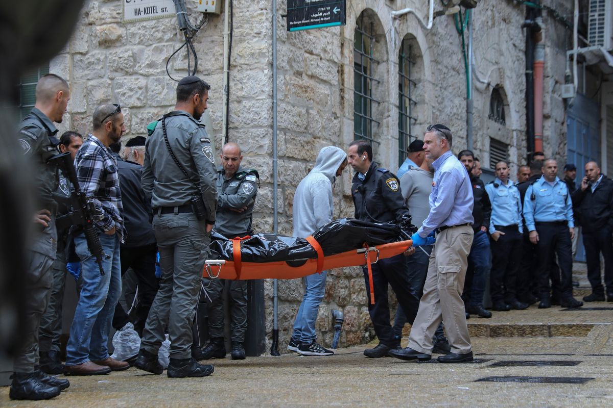 Israeli security personnel and members of Zaka Rescue and Recovery team carry the body of a Palestinian man who was fatally shot by Israeli police after he killed one Israeli and wounded four others in a shooting attack in Jerusalem
