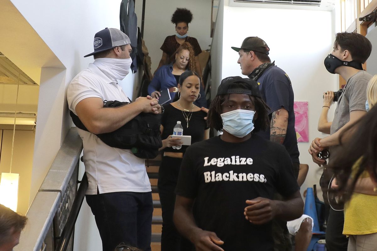 Marcus Henderson, lower center, and Naudia Miller, center, of Black Collective Voices, arrive to speak Thursday, June 25, 2020, at a news conference in Seattle. Miller said the goal of protesters who have been active in the CHOP (Capitol Hill Occupied Protest) zone and elsewhere in the city since the death of George Floyd in Minneapolis is to dismantle systemic racism and to continue organizing until all of their demands are met. (Ted S. Warren)