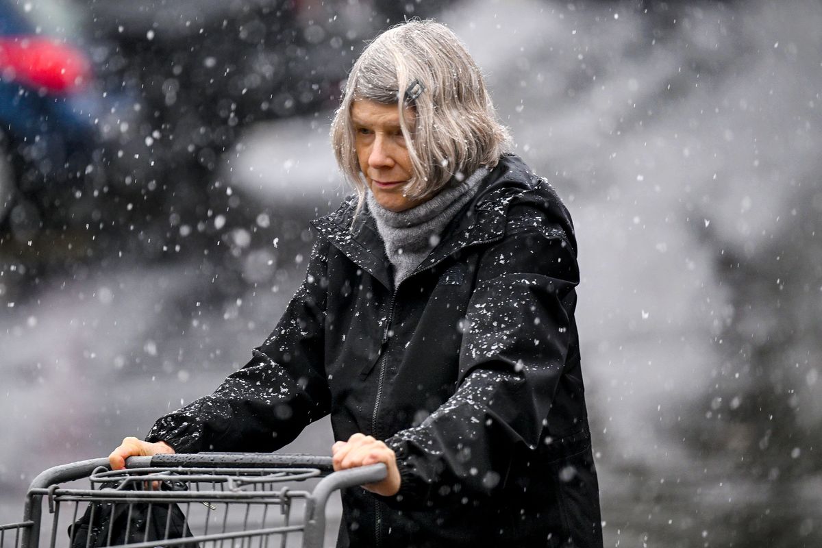 Pam Vail walks through the falling snow to return her cart to Huckleberry’s Natural Market on Thursday. Snow fell in Spokane the day after a powerful windstorm that left tens of thousands still without power in the region.  (Kathy Plonka/The Spokesman-Review)