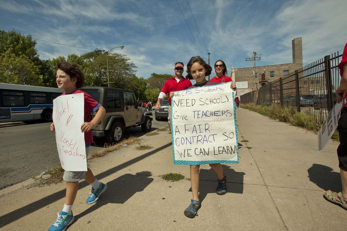 Children holding posters supporting striking teachers join a large group of public school teachers as they march on streets surrounding John Marshall Metropolitan High School on Wednesday, Sept. 12, 2012 in West Chicago. Teachers walked off the job Monday for the first time in 25 years over issues that include pay raises, classroom conditions, job security and teacher evaluations. (Sitthixay Ditthavong / Associated Press)