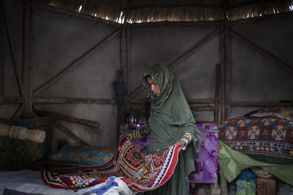 Priya spreads a quilt inside her bamboo home in Mirpur Khas, Pakistan. MUST CREDIT: Saiyna Bashir for The Washington Post.  (Saiyna Bashir/For The Washington Post)