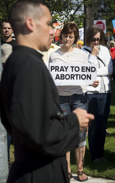 The Rev. Dennis Gordon from St. Joan of Arc Chapel in Coeur d’Alene prays the rosary as Helen Machtolf, holding sign, and others join in near the Spokane Planned Parenthood office on East Indiana Avenue. About 200 anti-abortion protesters picketed the office Saturday. (Colin Mulvany)