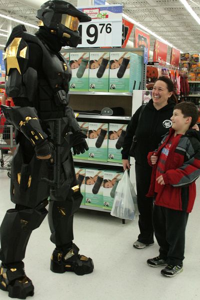 Jonathan Groves, a North Idaho College graphic design student, spent five months building this Master Chief suit for this morning's release of the Halo 4 video game. Groves, in the suit, greeted gamers at the GameStop and Wal-Mart on Mullan Avenue in Post Falls on Monday night before the game's release. Here, Derek Zaugg, 10, Hayden, and his mother, Shauna, ask questions. (Brian Walker/press)