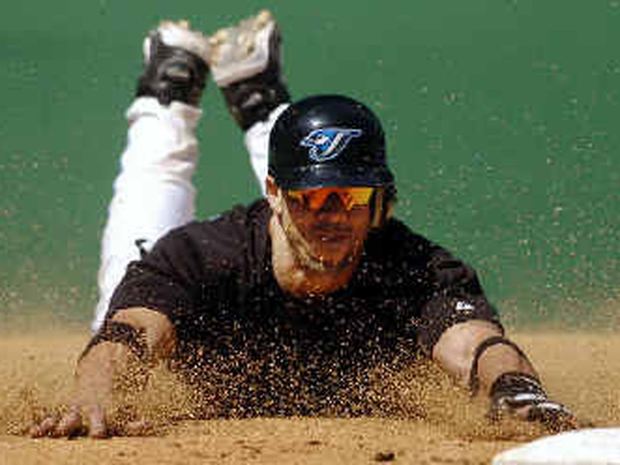 Carl Everett of the New York Mets, center, dives back to first