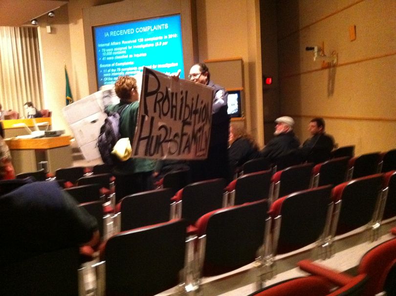 Spokane Police Detective Ben Estes asks Rebeckah Aubertin to leave the Spokane City Council Chambers after she stood and held signs during a presentation from Spokane Police Ombudsman Tim Burns on March 7, 2011.