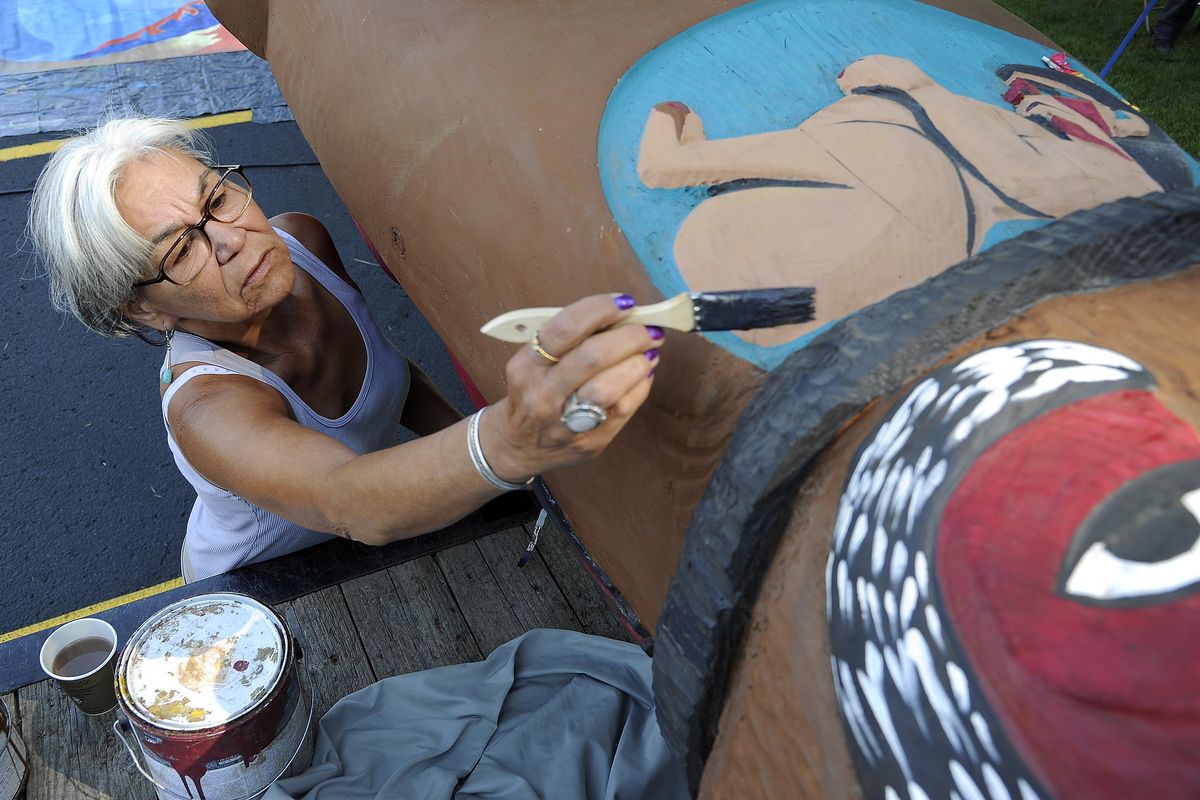 Totem pole painter and carver Lucy London touches up the paint on a traveling 19-foot totem pole that visited Spokane on Tuesday. The totem pole’s 2,500-mile, two-nation journey includes stops in communities impacted by increased coal and oil rail traffic. (Colin Mulvany)