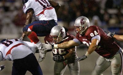
Arizona running back Chris Henry leaps past WSU defenders Greg Trent, center, and Mkristo Bruce on Saturday in Pullman. 
 (Christopher Anderson / The Spokesman-Review)