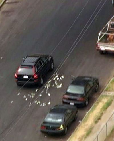 This image provided by KNBC-TV shows bank robbery suspects throwing money from their vehicle during a police pursuit Wednesday Sept. 12, 2012 in Los Angeles. The vehicle was eventually blocked by another vehicle and the suspects were arrested. (Knbc-tv)