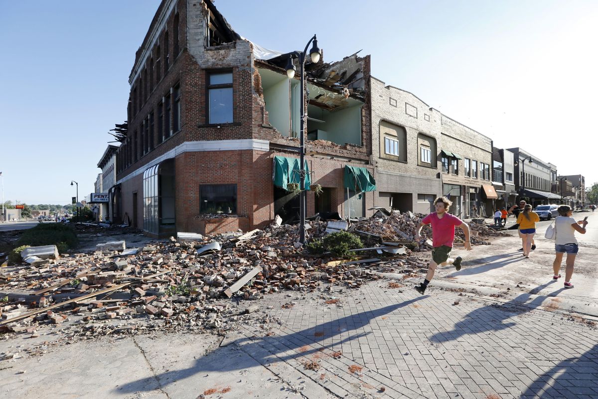 A local resident runs past a tornado-damaged building on Main Street on Thursday, July 19, 2018, in Marshalltown, Iowa. Several buildings were damaged by a tornado in the main business district in town including the historic courthouse. (Charlie Neibergall / AP)