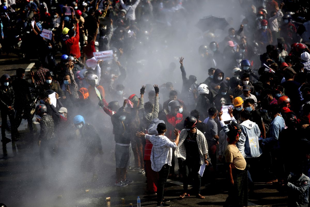 Protesters are sprayed with water fired from a police truck