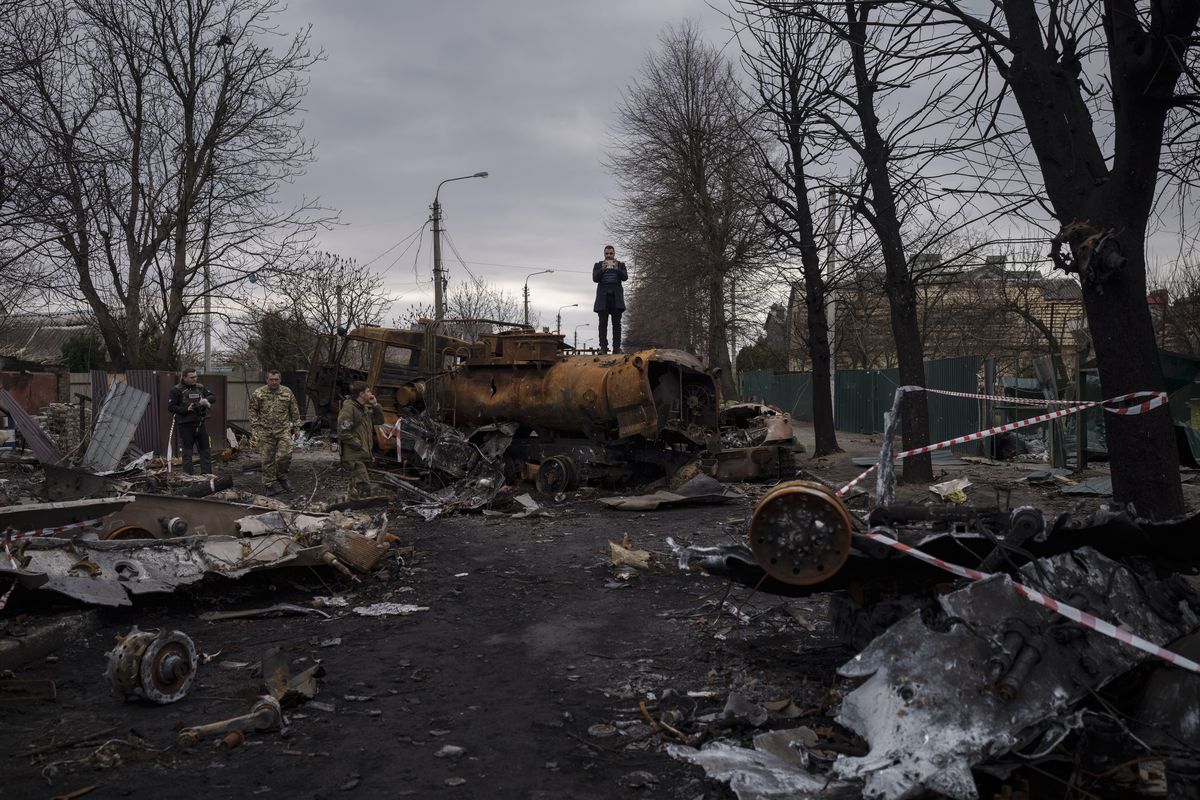 FILE - A journalist stands atop a destroyed vehicle after fights between Russian and Ukrainian forces in Bucha, on the outskirts of Kyiv, Ukraine, April 6, 2022. Ukrainian leaders have encouraged journalists to document what is happening in the country.  (Felipe Dana)